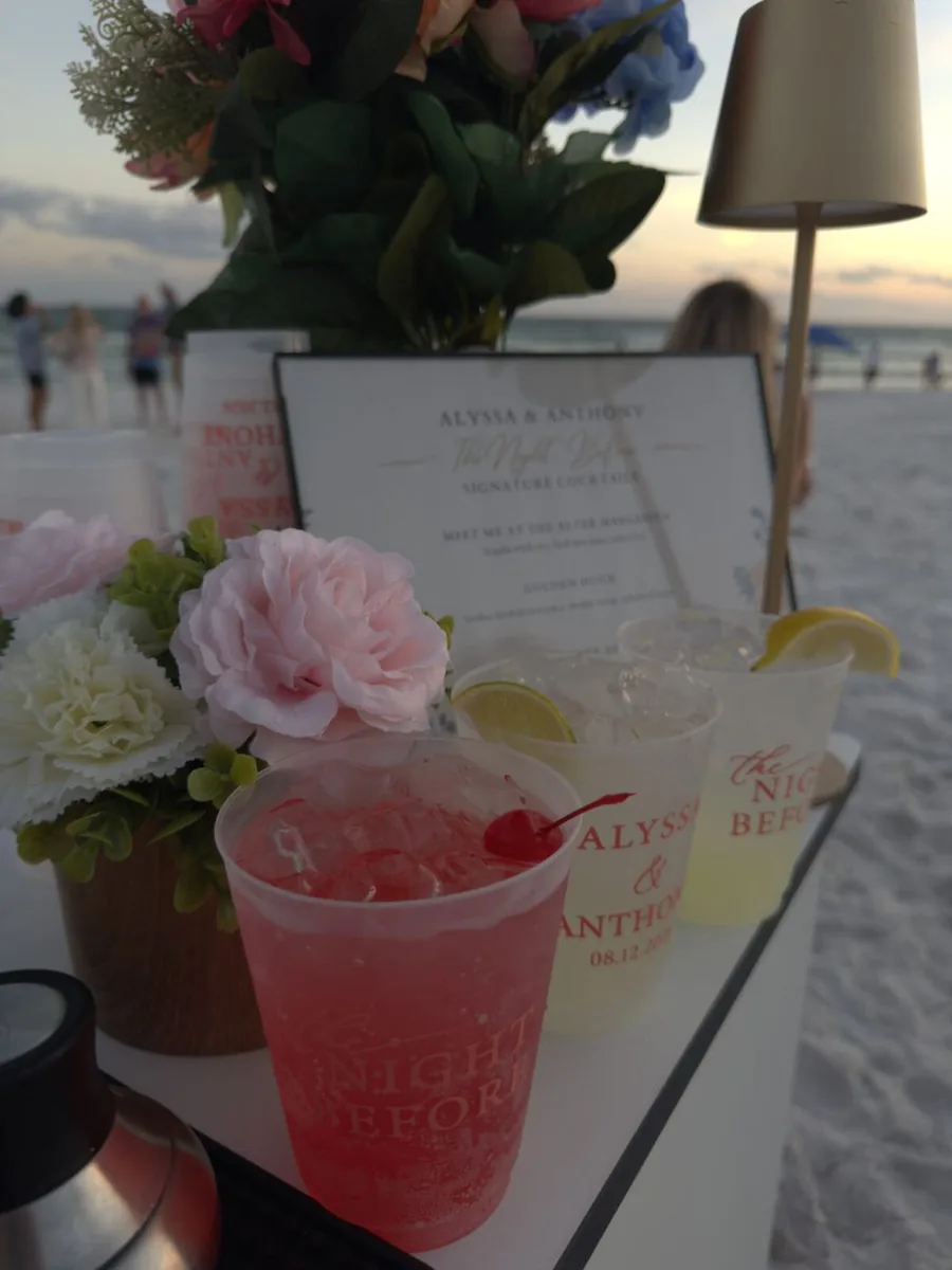 Personalized wedding cocktails and pink flowers on the bar at sunset